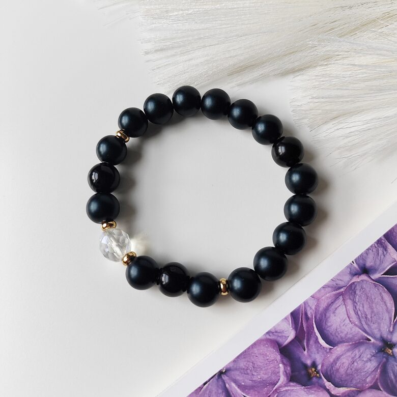 Melna rokassprādze ar zeltītām detaļām