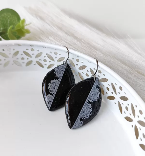 Black polymer clay earrings with a detailed lace pattern texture